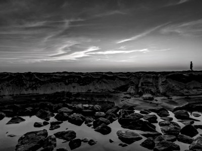Grayscale Photo Of Person Walking On Rocks photo