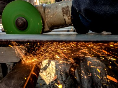 Person Using Green And Grey Angle Grinder On Sheet Of Metal photo