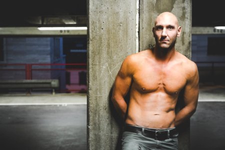 Photography Of A Shirtless Man Leaning On Wall photo