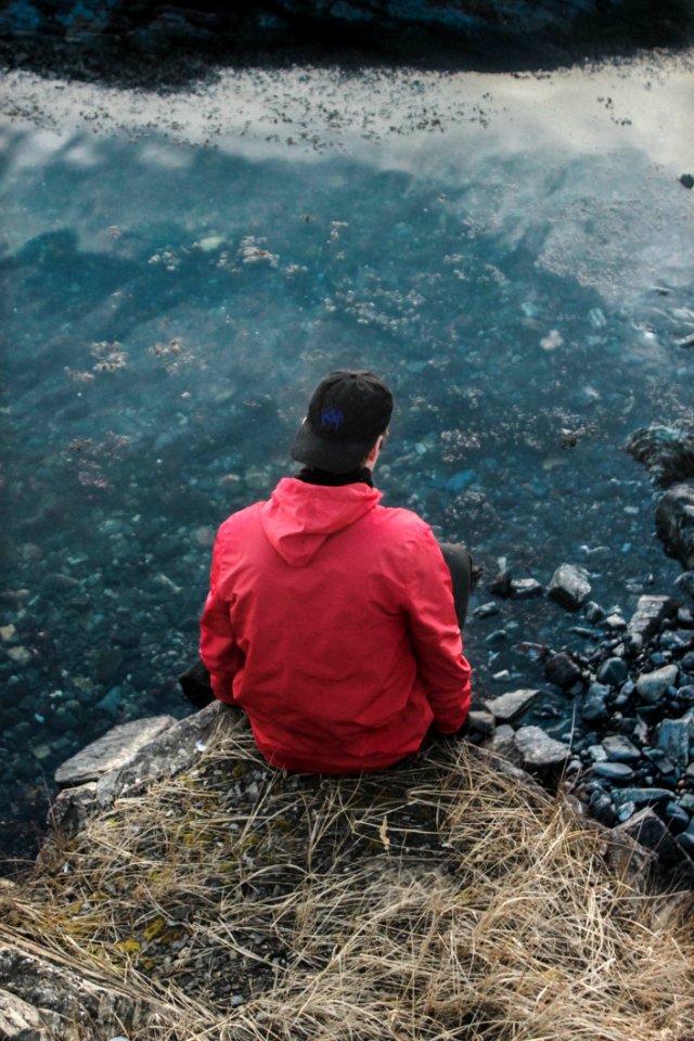 Man In Red Hoodie Sitting On Cliff
