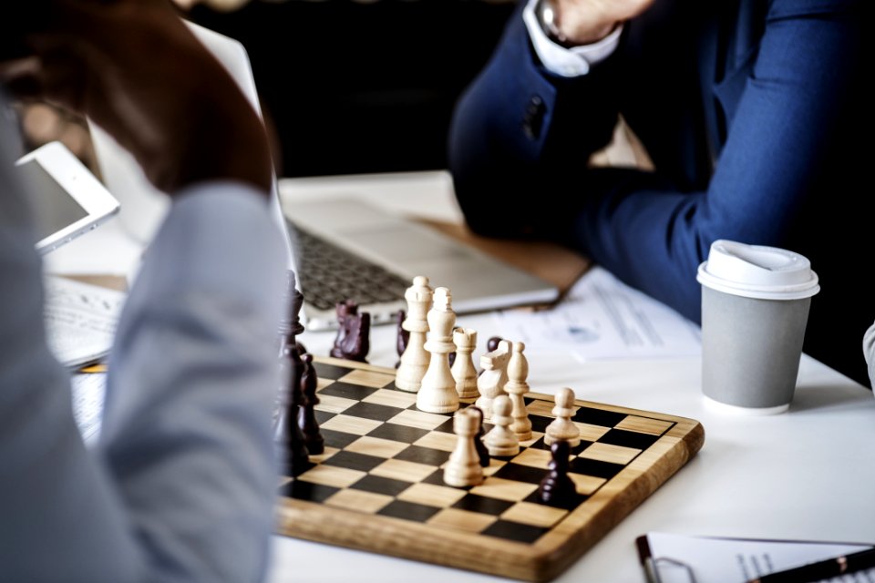 Photo Of Brown Wooden Chess Set On Table Beside White And Gray Disposable Cup