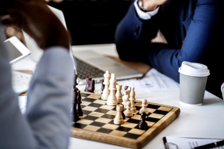 Photo Of Brown Wooden Chess Set On Table Beside White And Gray Disposable Cup photo