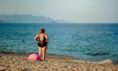 Woman In Black Swimsuit Standing On Beach Shore photo