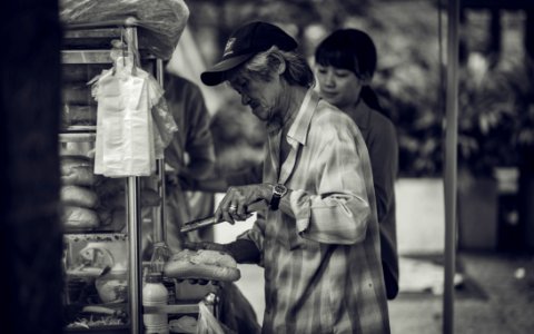 Grayscale Photo Of A Man Selling Sandwiches On The Streets photo