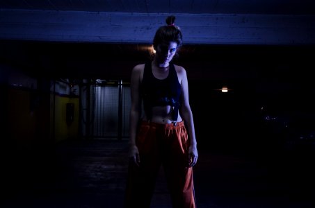 Woman With Black Sports Bra And Red Pants In Dark Room photo
