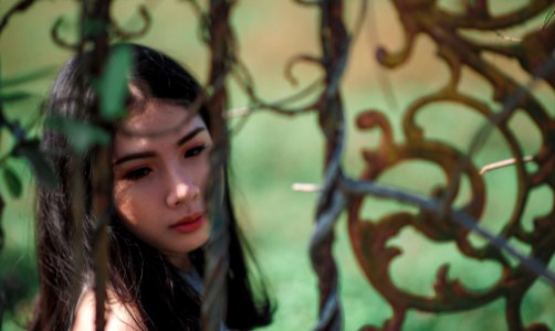 Woman With Green Background Near Black Metal Gate