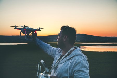Man In Gray Jacket Holding Black Drone