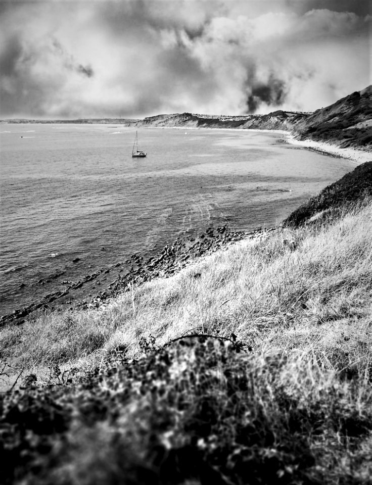 Grayscale Photography Of Boat On Body Of Water Near Mountain