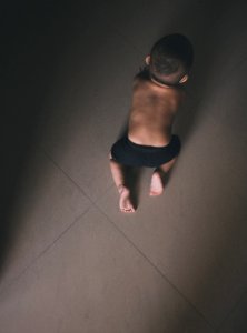 Toddler In Black Shorts Crawling On Grey Floor Tiles
