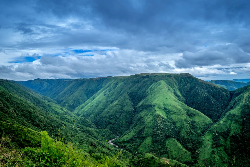 Landscape Photography Of Green Mountains Under Cloudy Sky