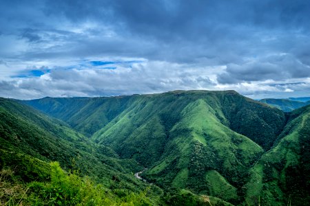 Landscape Photography Of Green Mountains Under Cloudy Sky