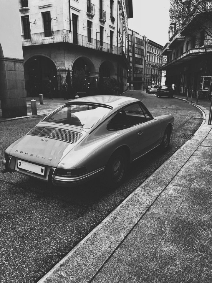 Grayscale Photo Of Vintage Vehicle On Road Near Building