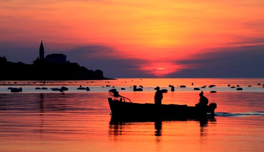 Silhouette Of Two Men On Boat Under Orange Sky photo
