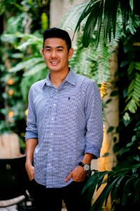 Man Wearing Blue Dress Shirt Standing Beside Green Plant photo