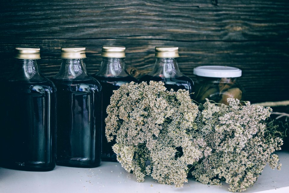 Four Clear Glass Bottles With Black Liquid Near Brown Flower Bouquet