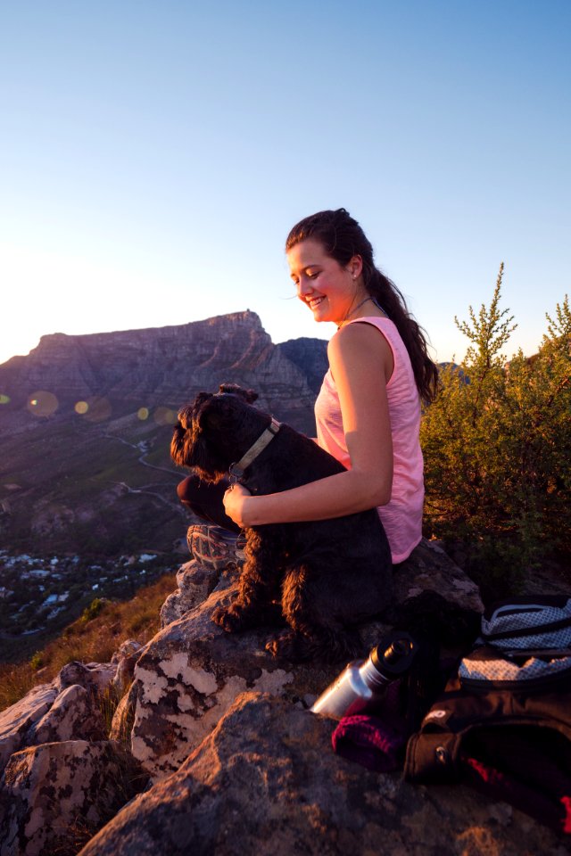 Woman Wearing Pink Tank Top Sitting On Rock Beside Dog photo