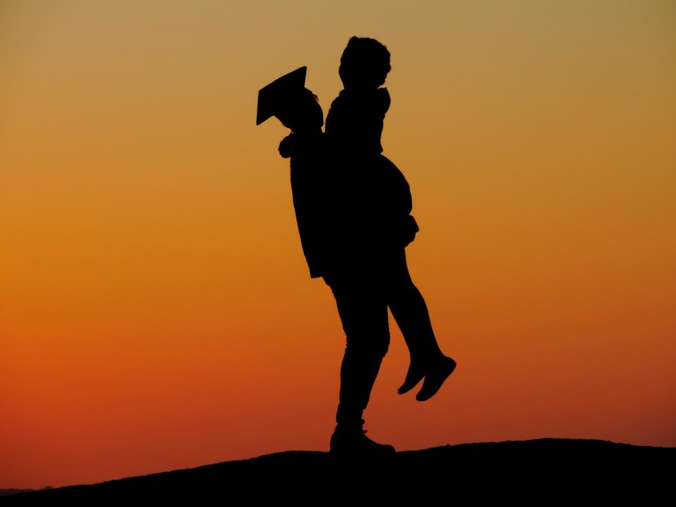 Silhouette Photo Of Man Carrying Woman Under Orange Sky