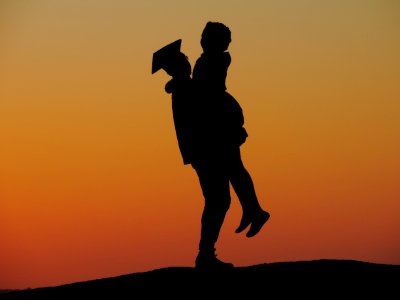 Silhouette Photo Of Man Carrying Woman Under Orange Sky photo