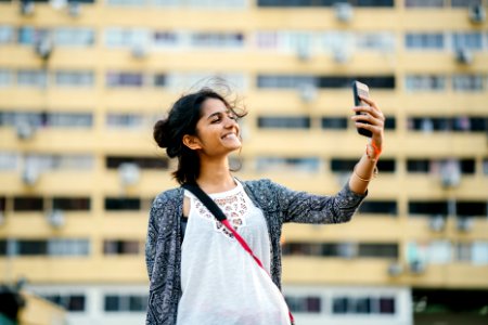 Smiling Woman Holding Black Smartphone photo