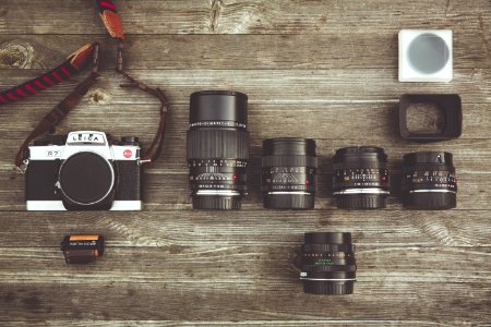 Black And Gray Dslr Camera With Assorted Lenses On Brown Wooden Surface photo