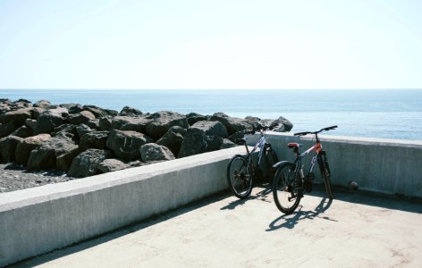 Two Bicycles Behind Gray Concrete Wall photo