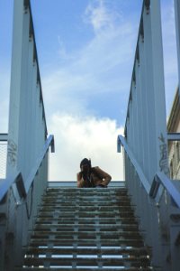 Person In Brown Coat On Bridge Under Cloudy Blue Sky photo