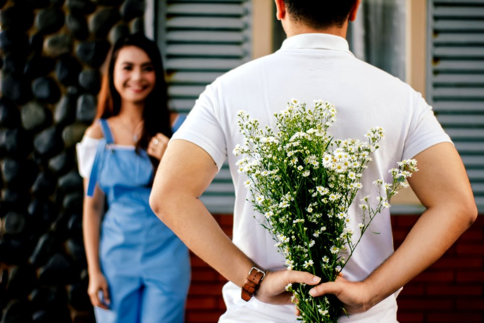 Man Holding Babys-breath Flower In Front Of Woman Standing Near Marble Wall
