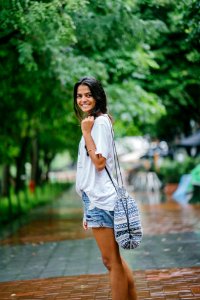 Shallow Focus Photography Of Woman In White Shirt And Blue Denim Shorts On Street Near Green Trees