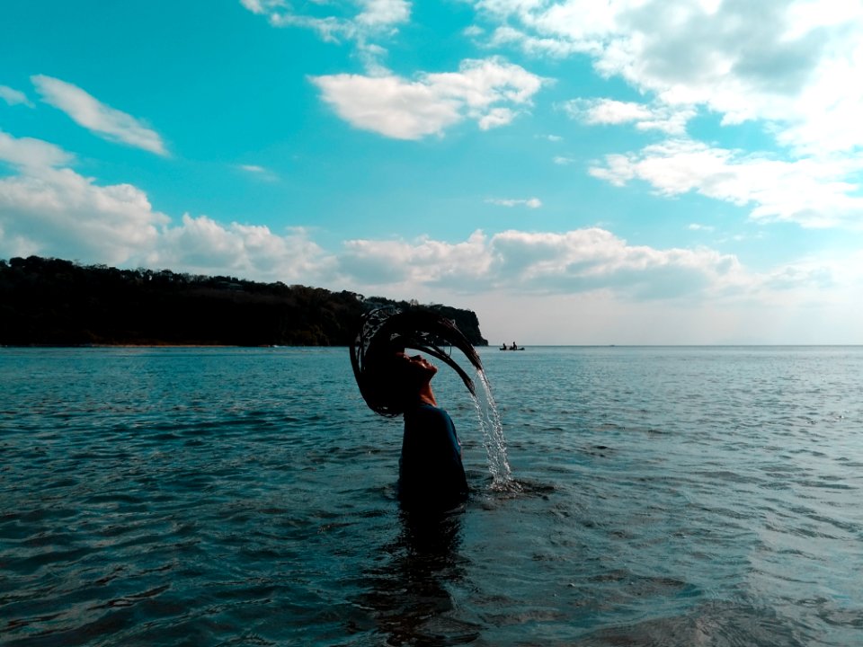 Woman In Black Shirt Lifting Her Hair From Water During Noontime