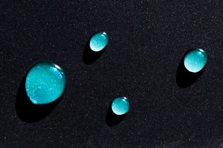 Four Water Droplets On Black Surface