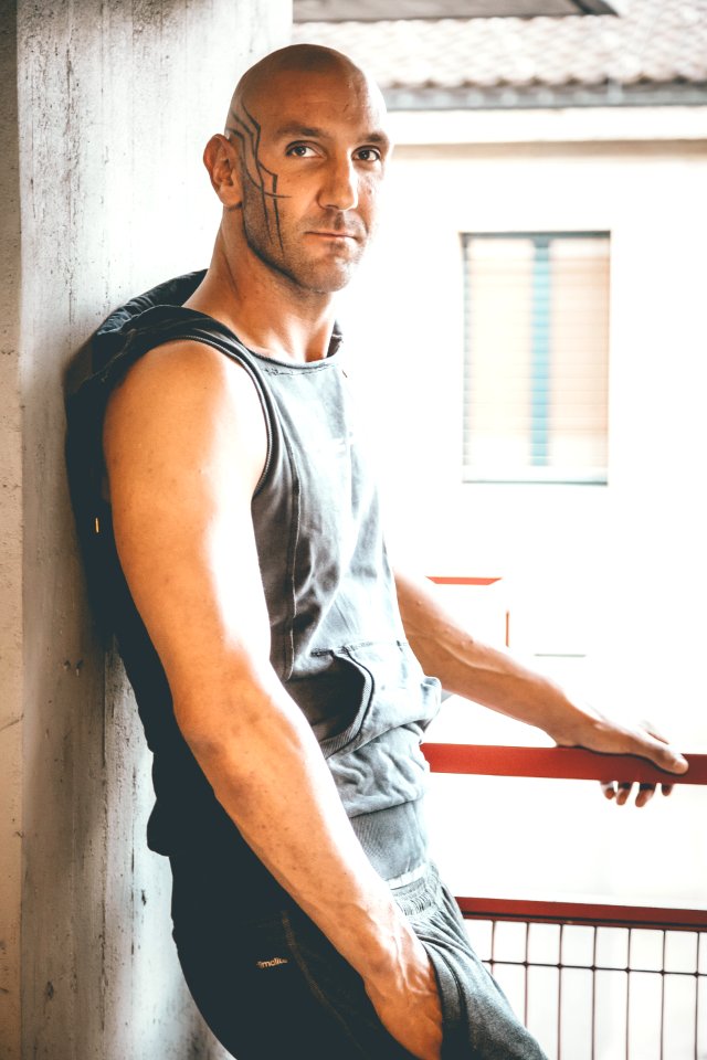 Man In Black Sleeveless Hoodie Leaning On Gray