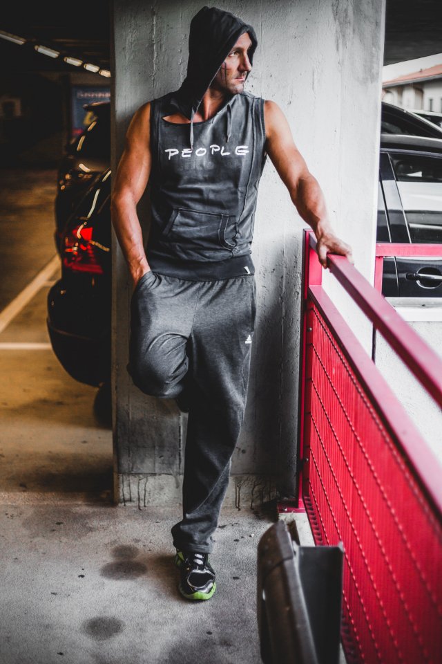 Man Wearing Black Tracksuit Standing Beside Red Metal Fence photo