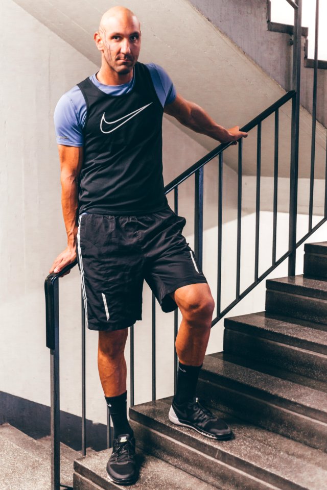 Man Wearing Black Nike Tank Top Placing His Hands On Black Stair Handrail photo