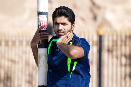 Man In Blue And Green T-shirt Holding On White Post