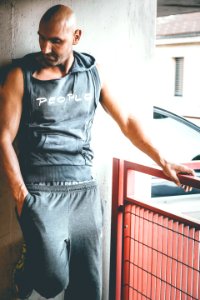 Photography Of Man In Gray Sleeveless Top Standing Near Gray Concrete Wall photo