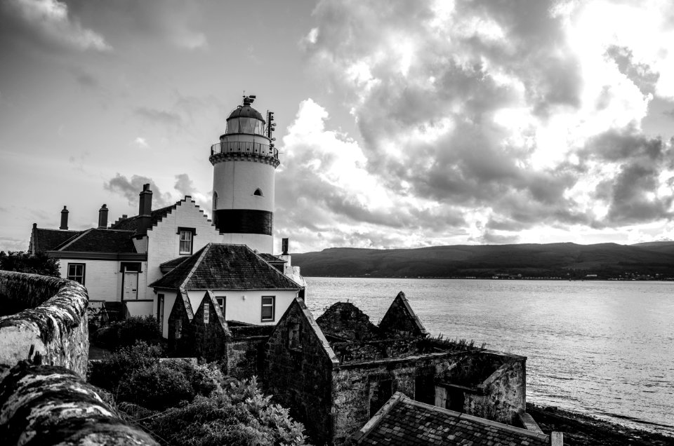 Grayscale Photo Of Lighthouse On Rocky Cliff