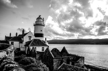 Grayscale Photo Of Lighthouse On Rocky Cliff photo