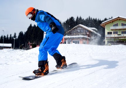 Person In Blue Coveralls Snowboarding On Snow