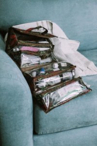 Items Inside Brown Hanging Organizer On Green Sofa