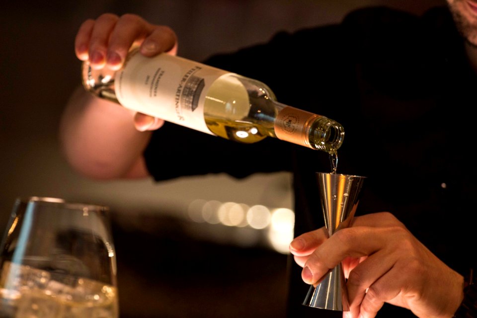 Person Pouring Wine On Grey Jigger