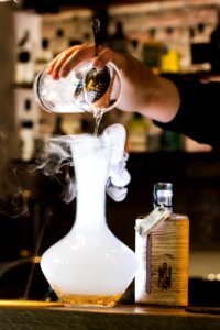 Person Pouring Liquid Into Smoking Glass Container