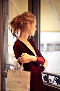 Woman Holding White Paper Bag While Looking At The Window