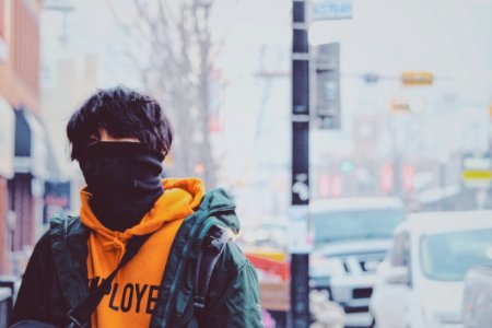 Man In Orange Pullover Hoodie And Green Jacket Covered With Black Mask