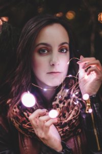 Woman Wearing Leather Jacket And Leopard Print Scarf Holding String Light photo