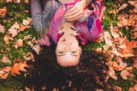 Woman Lying Down On Green Grass Field Holding Brown Leaf photo