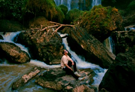 Photo Of Man Sitting On Gray Rock Surrounded By Water Falls photo