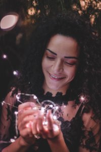 Woman Holding String Lights While Smiling
