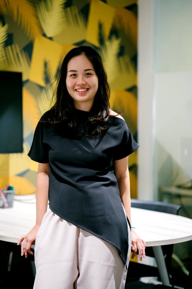 Woman Sits On White Wooden Table Behind Yellow And White Concrete Wall