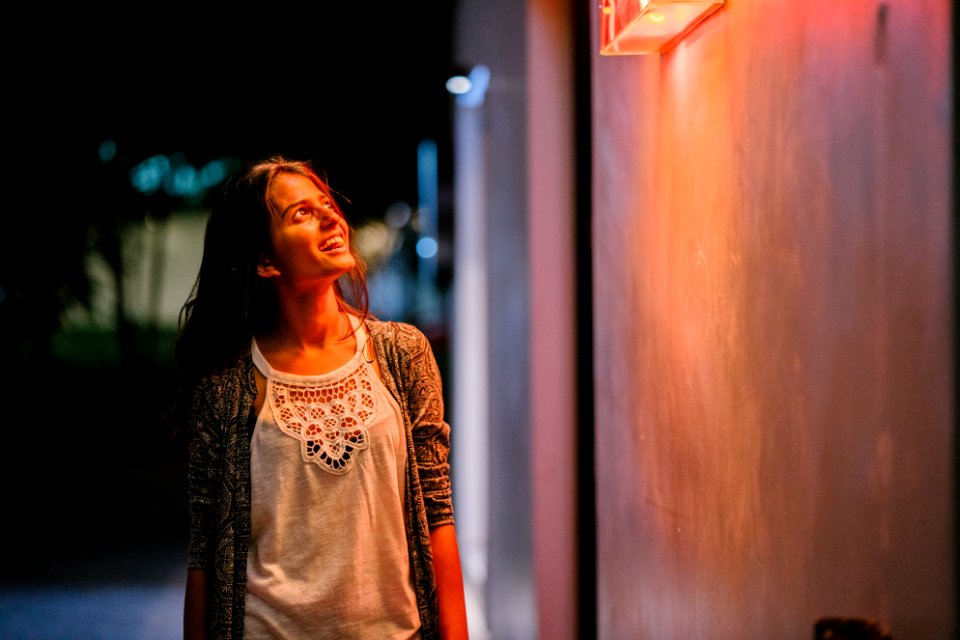 Woman In Gray Cardigan Standing Near Wall During Nighttime