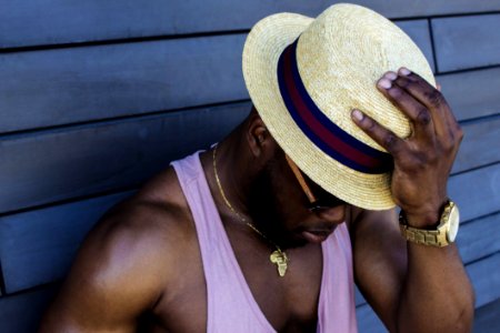 Man Wearing Purple Tank Top Gold-colored Necklace Gold-colored Watch Sunglasses And Beige Fedora Hat Outfit photo